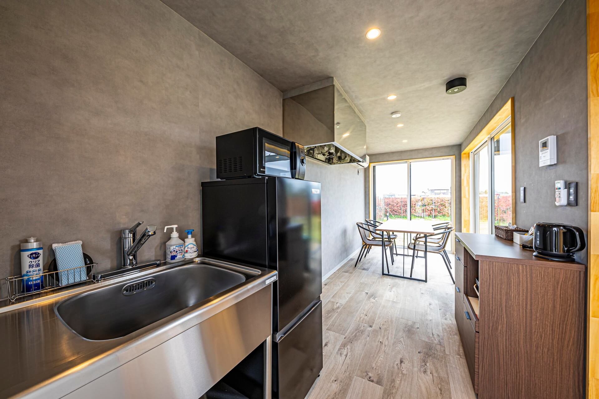 モルタル風の壁紙と古木風の床がかっこいい空間に仕上がっております。雨天時は中でBBQコンロが使えるように換気扇も完備しています。