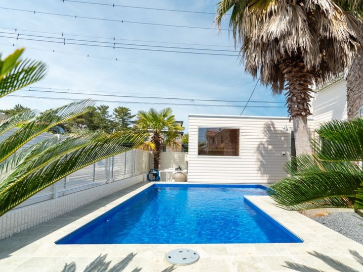 ブルーのプールの底とホワイトウッド調ラップサイディング風の外壁を張ったユニットハウスがマッチしています。