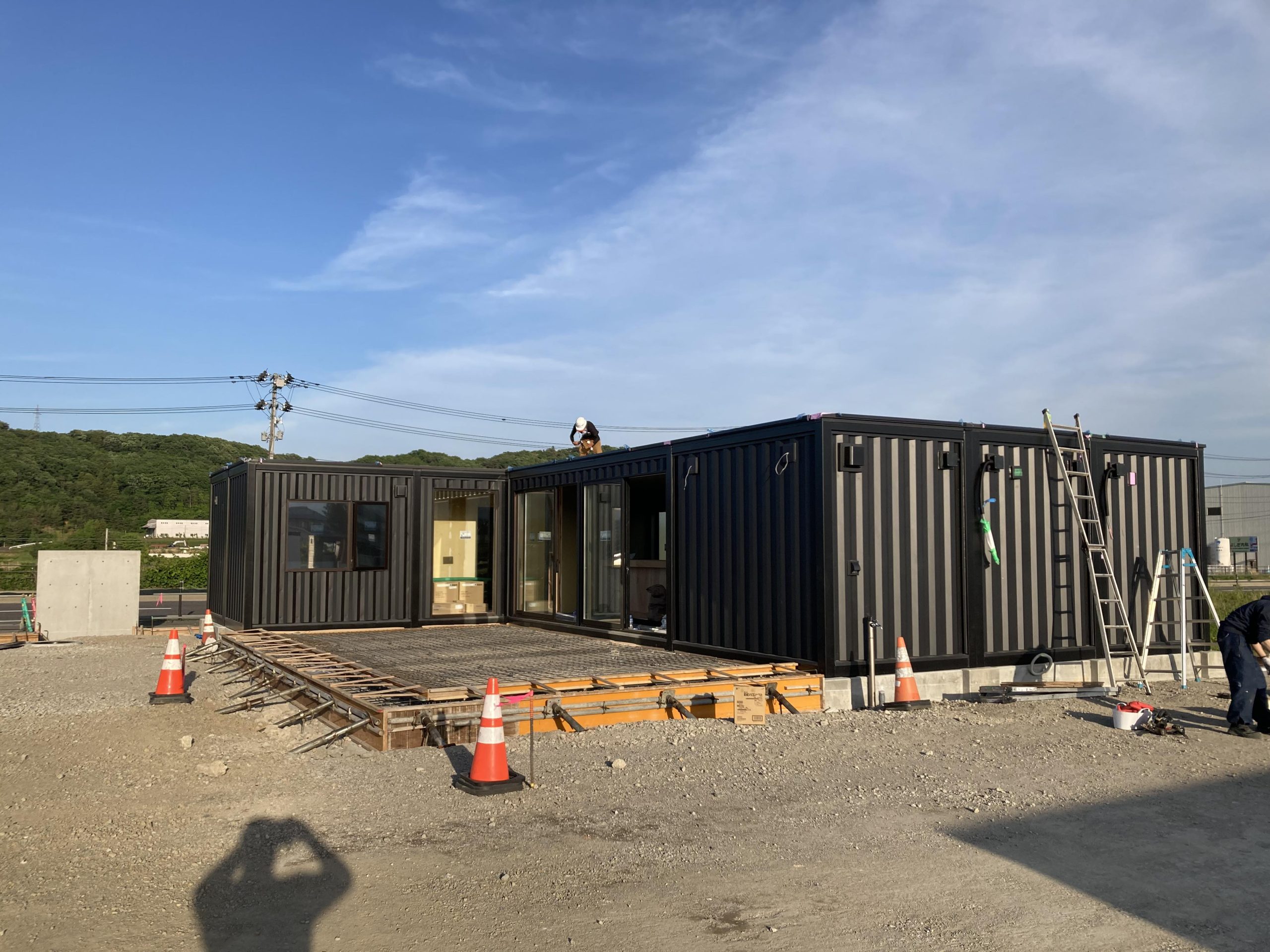 外観はコンテナなハウス調の凸凹した無骨なデザインで、ブラック色の外壁を選定いたしました。画像は施工途中ですが大きなサッシから土間に出来ることができ、この土間をテラスのようにして活用するお洒落なオフィスを計画しています。