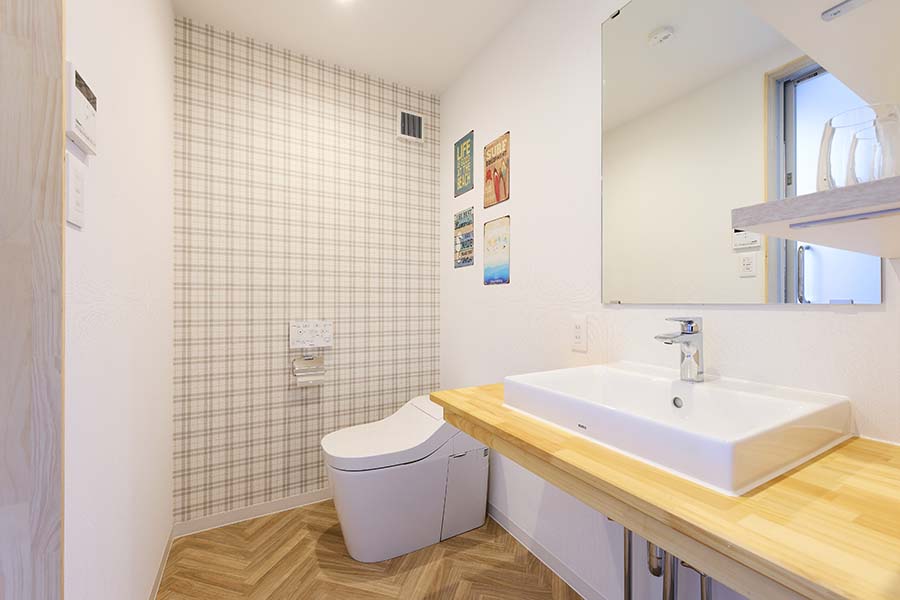 トイレはノータンクでスタイリッシュに、チェック柄の壁紙をアクセントに、造作手洗い器もお洒落です。